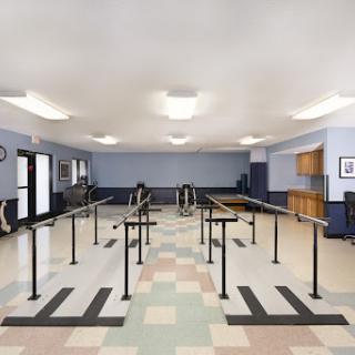 A spacious physical therapy room equipped with parallel bars and exercise areas.