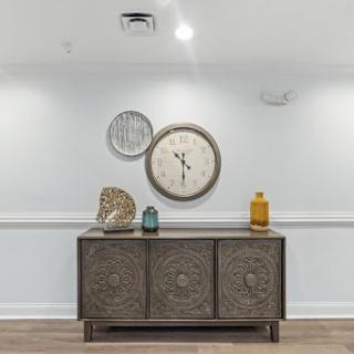 A stylish interior setup featuring a decorative cabinet, wall clock, and artistic elements.