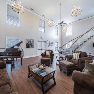 A spacious, elegantly designed living room featuring a grand piano and modern furniture.