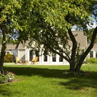 A cozy house with a well-maintained backyard surrounded by lush green trees and lawn.