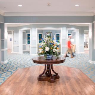 A welcoming lobby featuring a floral centerpiece on a wooden table, surrounded by stylish decor and bright lighting.