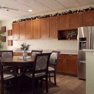 A cozy kitchen and dining area featuring wooden cabinets, a round dining table with chairs, and a stainless steel refrigerator.