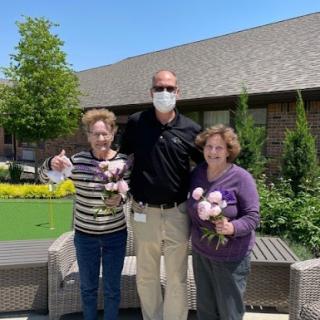 A joyful moment shared among friends in the garden, celebrating with flowers.