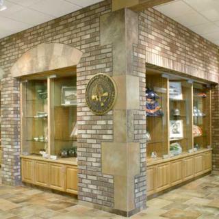 A corner of a museum with brick walls and display cases featuring various artifacts.