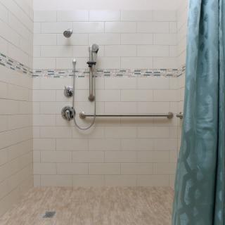 A tiled shower area with a grab bar and curtain.
