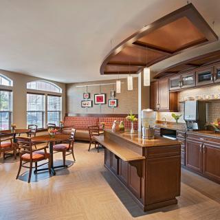A modern kitchen and cafe area with wooden furniture and a seating space.