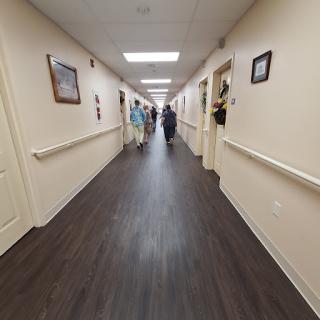 A wide view of a well-lit hallway in a healthcare facility with people walking.