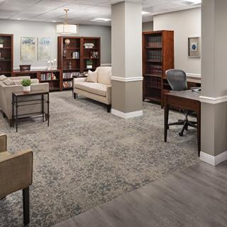 A spacious and well-furnished office lobby with comfortable seating and bookshelves.