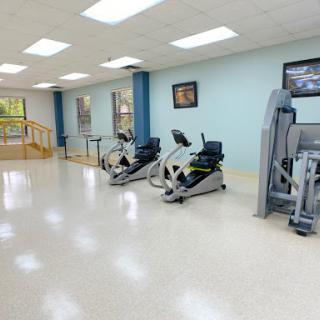 A spacious and well-lit gym area equipped with exercise machines, ideal for fitness and rehabilitation.