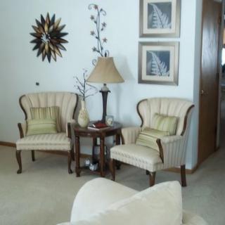 A cozy living room corner with two elegant armchairs and a side table lamp, complemented by wall art.