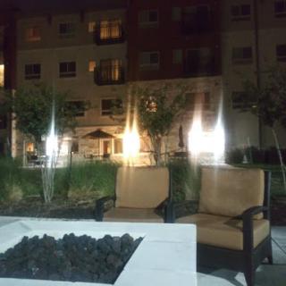 A cozy outdoor seating area with chairs around a fire pit, set against the backdrop of an apartment complex at night.