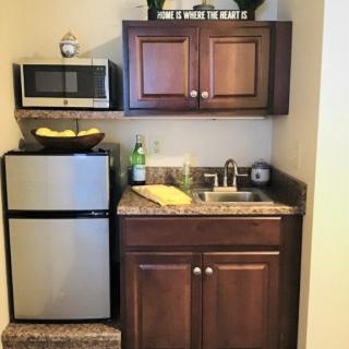 A compact kitchenette with a microwave, refrigerator, and cabinetry.
