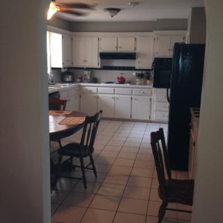 A view of a kitchen and dining area with white cabinets, a table, and chairs.
