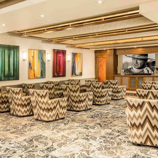 A modern lounge area featuring stylish chairs and vibrant artwork on the walls.
