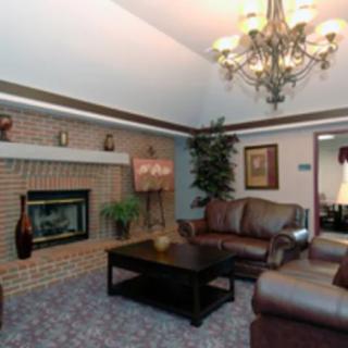 A cozy living room with a chandelier, brick fireplace, and comfortable seating.