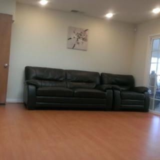 A modern living room with a black leather sofa and wooden flooring.