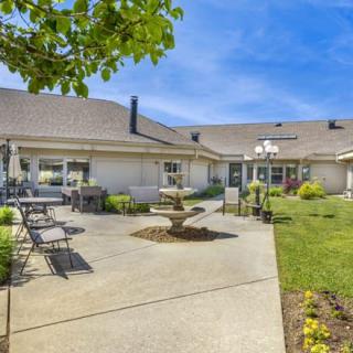 Spacious backyard with patio furniture and a well-maintained garden on a sunny day.