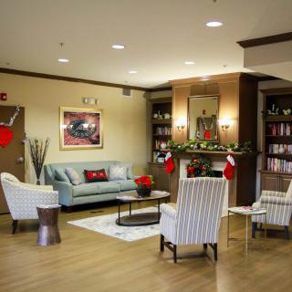 A cozy living room with holiday decorations, featuring comfortable seating and a fireplace.