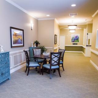 A well-lit hallway with a small table and chairs, adorned with artwork and decor.