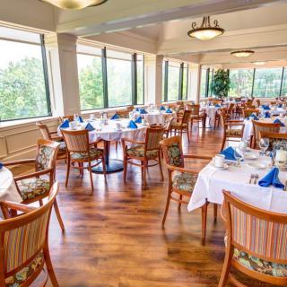 An elegant restaurant dining room with neatly arranged tables and large windows.