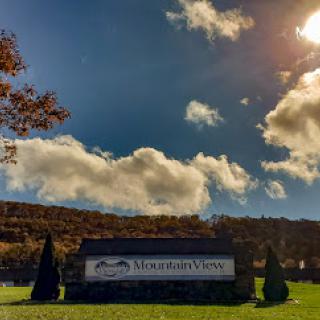 A picturesque view featuring a sign against a backdrop of mountains and a beautiful sky.