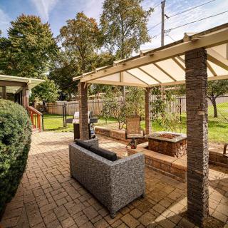 A beautiful outdoor patio area featuring comfortable seating under a pergola in a well-maintained backyard.