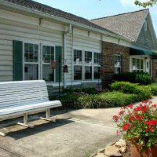 A charming building with a white bench, colorful flowers, and well-maintained landscaping.