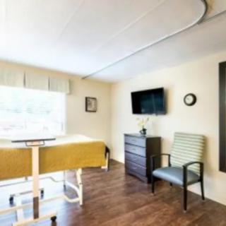 A hospital room with a bed, television, and seating area.