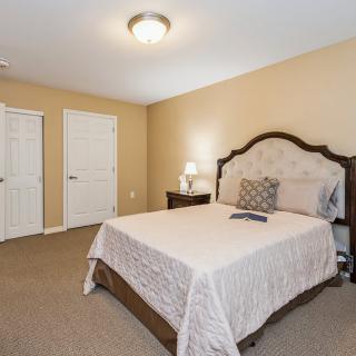 A cozy bedroom with a neatly made bed, warm lighting, and simple decor.