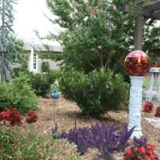 A beautifully landscaped garden with various plants and a decorative sculpture.