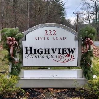 Welcome sign for Highview of Northampton located at 222 River Road, adorned with festive decorations.
