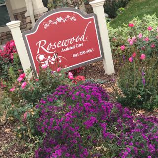 A vibrant garden featuring colorful flowers alongside the Rosewood sign.