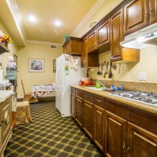A cozy kitchen with wooden cabinets, a stove, and a refrigerator on a checkered floor.