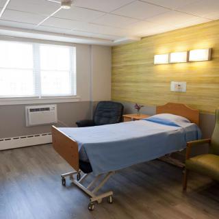 A well-lit hospital room with a bed and chairs.