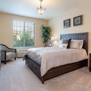 A cozy and well-decorated bedroom with a large window allowing natural light to fill the space.