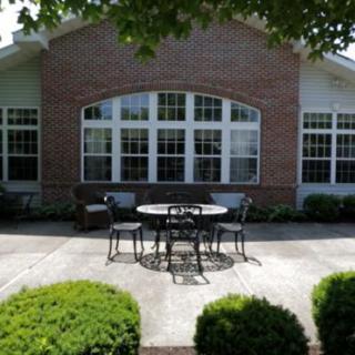 A peaceful patio area with a table and chairs in front of a brick building.
