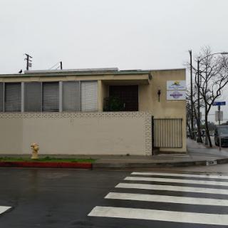 A commercial building viewed on a rainy day, featuring a crosswalk in the foreground.