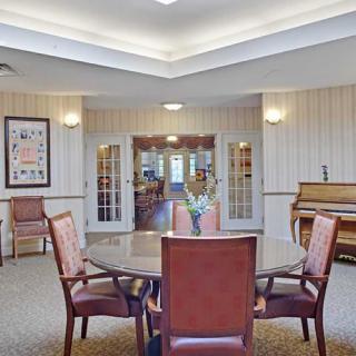 A cozy room with a table surrounded by chairs and a piano in the corner.