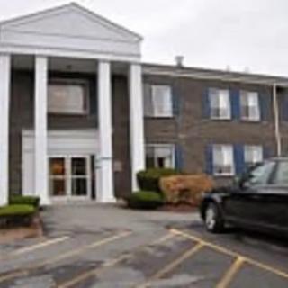 A two-story building with columns at the entrance and a parked car in front.