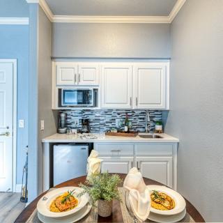 A modern and compact kitchen with white cabinets, a small dining table set for two, and stylish decor.