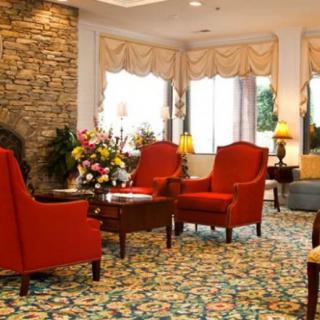 A cozy living room with red chairs, a stone wall, and floral decorations.