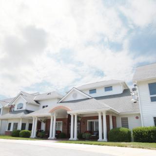 A residential building with a grand entrance under a partly cloudy sky.
