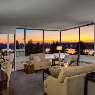 A cozy living room with modern furniture and large windows offering a breathtaking sunset view.