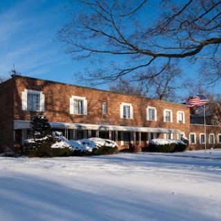 A charming brick house blanketed in snow under a clear blue sky.