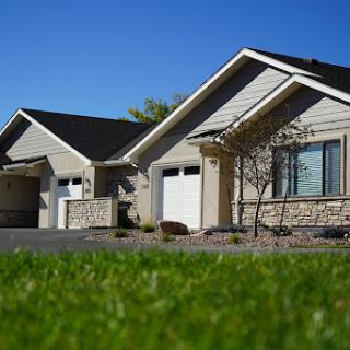 A picturesque view of modern houses with well-maintained lawns under a clear blue sky.