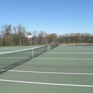 An empty outdoor tennis court under a clear blue sky.