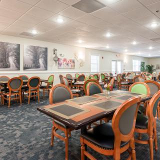 A well-lit dining room with neatly arranged tables and chairs, featuring elegant decor.