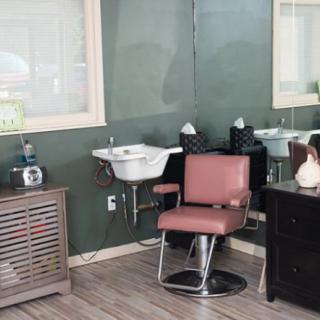A salon interior featuring a barber chair, sink, and mirror.