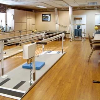 A physical therapy room equipped with parallel bars and other rehabilitation equipment.