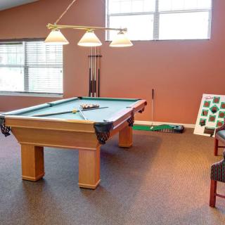 A well-lit game room featuring a pool table and seating area.